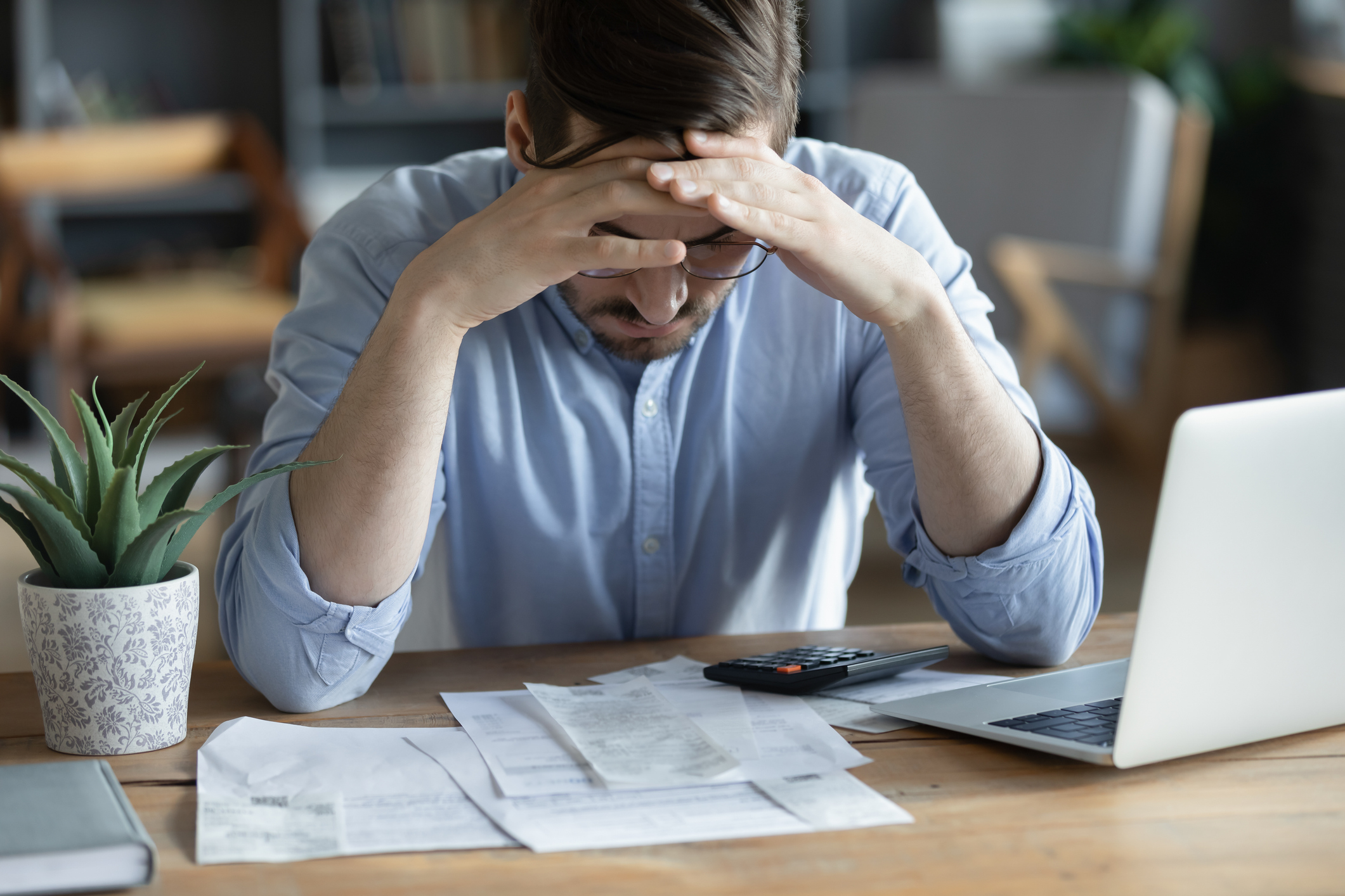 man checking bills, anxiety about debt or bankruptcy, financial problem, bank debt or lack of money, unhappy frustrated young male sitting at work desk with laptop and calculator
